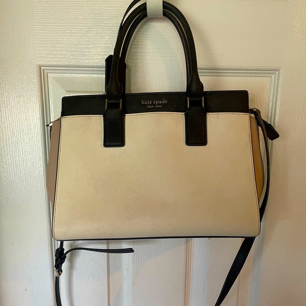 Cute used Kate Spade bag. It is a cream color w/tan sides, black accents.